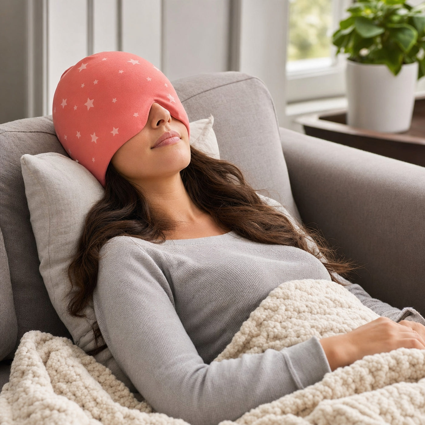 Woman relaxing on sofa wearing the migraine relief cap with eye mask down