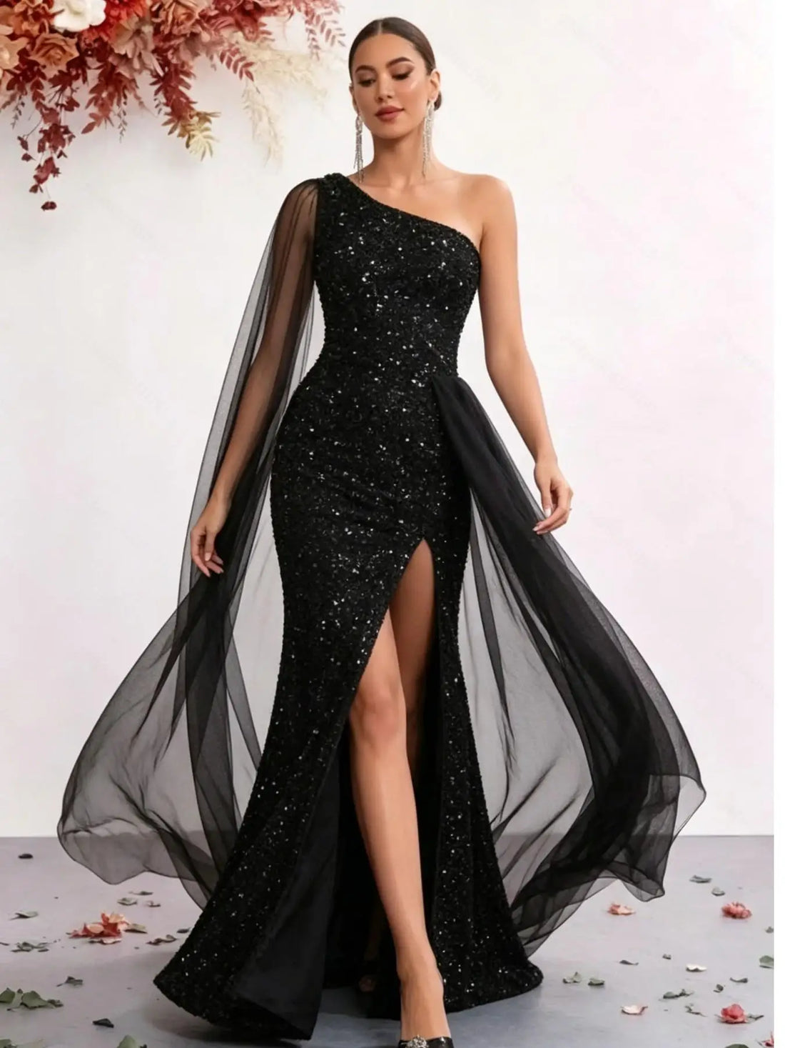 Model wearing a one-shoulder black sequin mermaid gown with tulle panel
